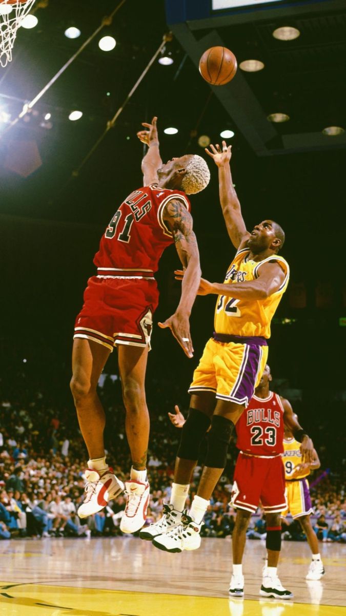 Dennis Rodman leaping for a rebound surrounded by opponents in an NBA game